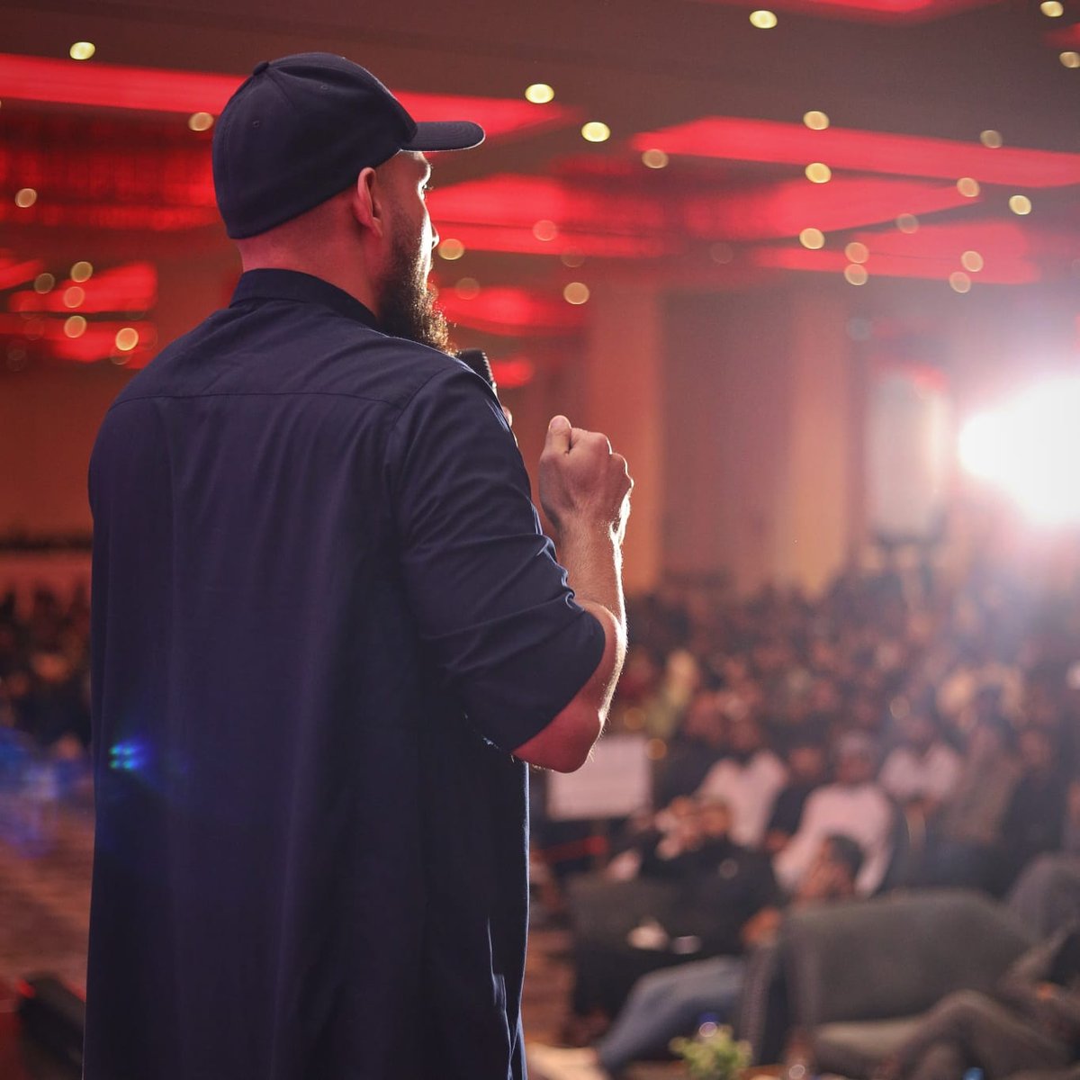 Abu Saad speaking on stage at a fitness and mentorship event